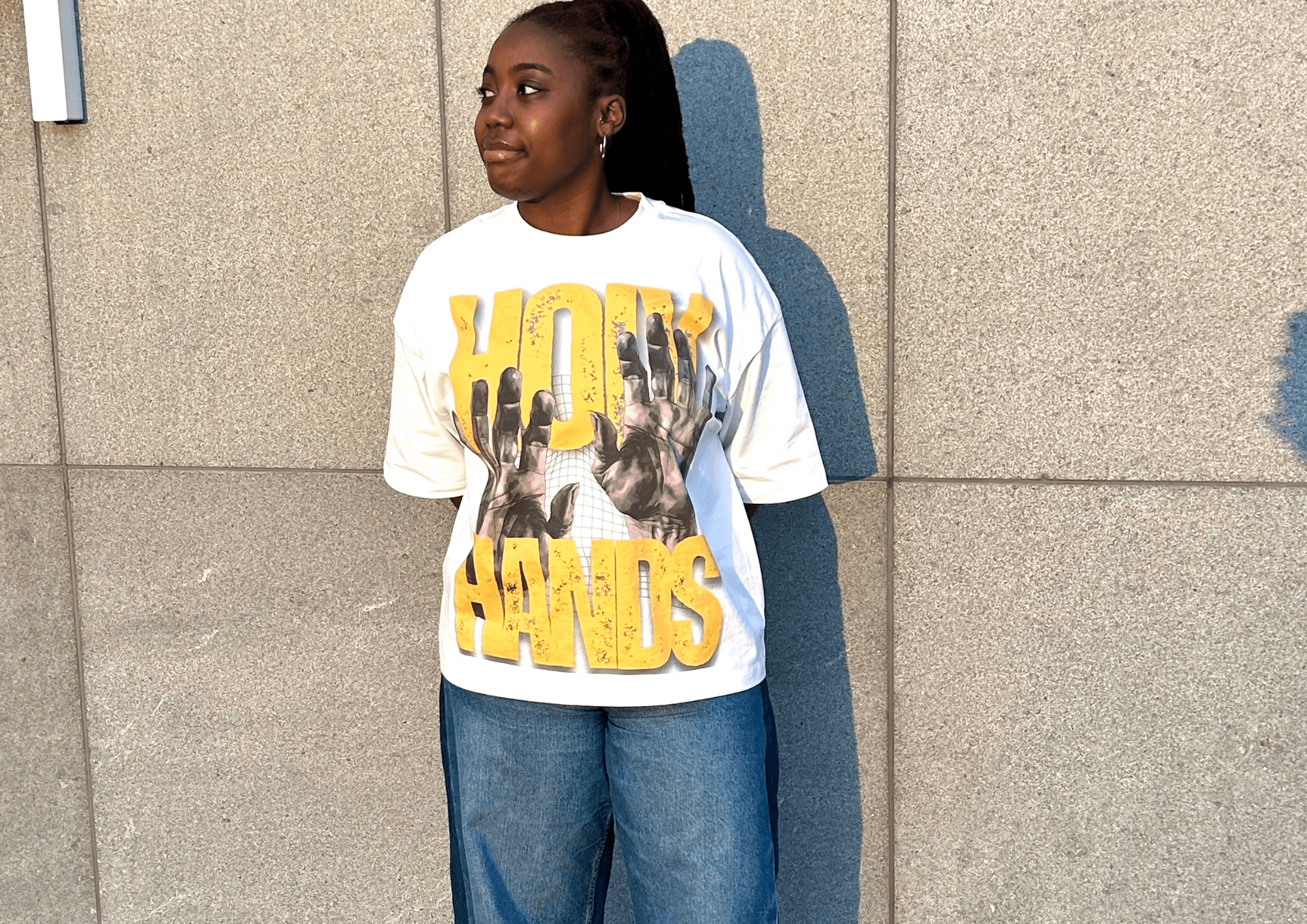 Model wearing an oversized graphic t-shirt against a stone wall