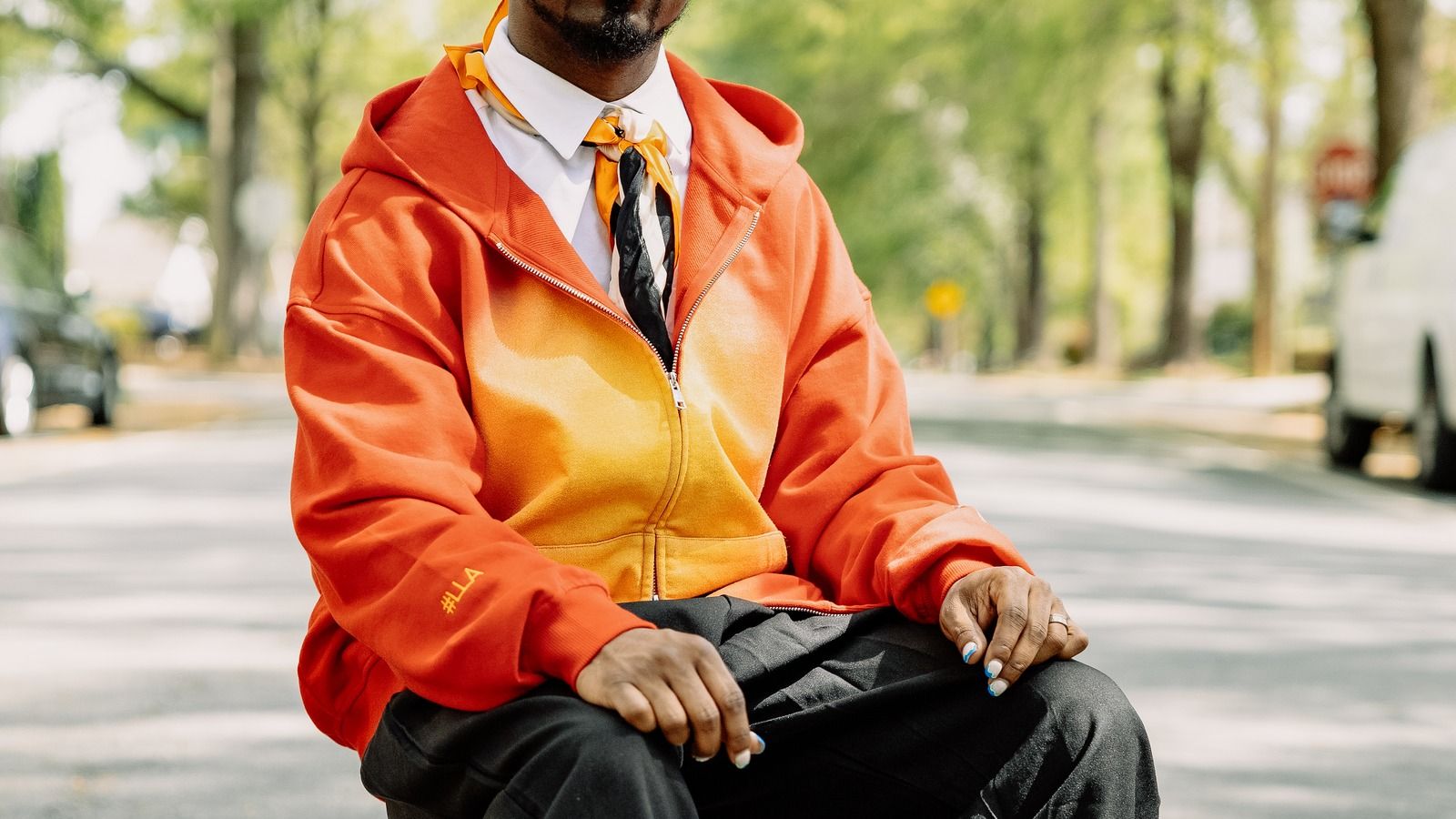 PODpartner 440GSM Heavyweight Faded Hoodie real customer lifestyle: orange faded zip-up hoodie worn by model in natural street setting, demonstrating retail-quality finish and fit at the $39.61 per-unit production cost referenced in the worked cost breakdown